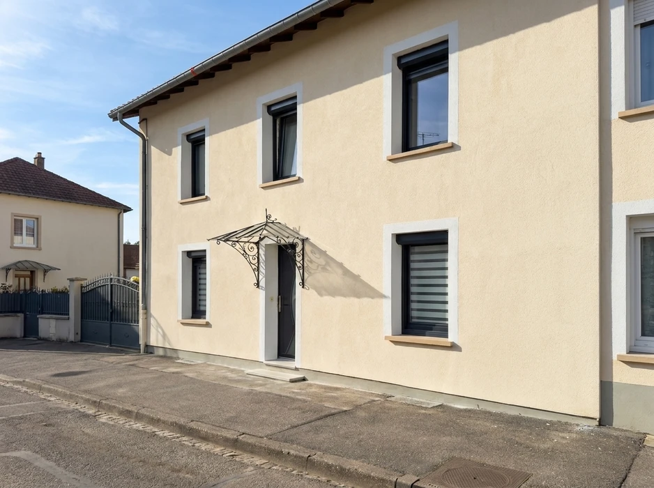 Façade d'une maison de ville à deux étages, enduit lisse beige clair, encadrements de fenêtres en pierre naturelle