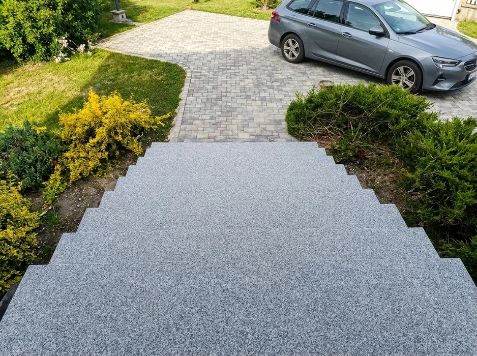 Escalier extérieur en granit gris flammé, vue plongeante, 5 marches larges descendant vers une allée en pavés autobloquants multicolores