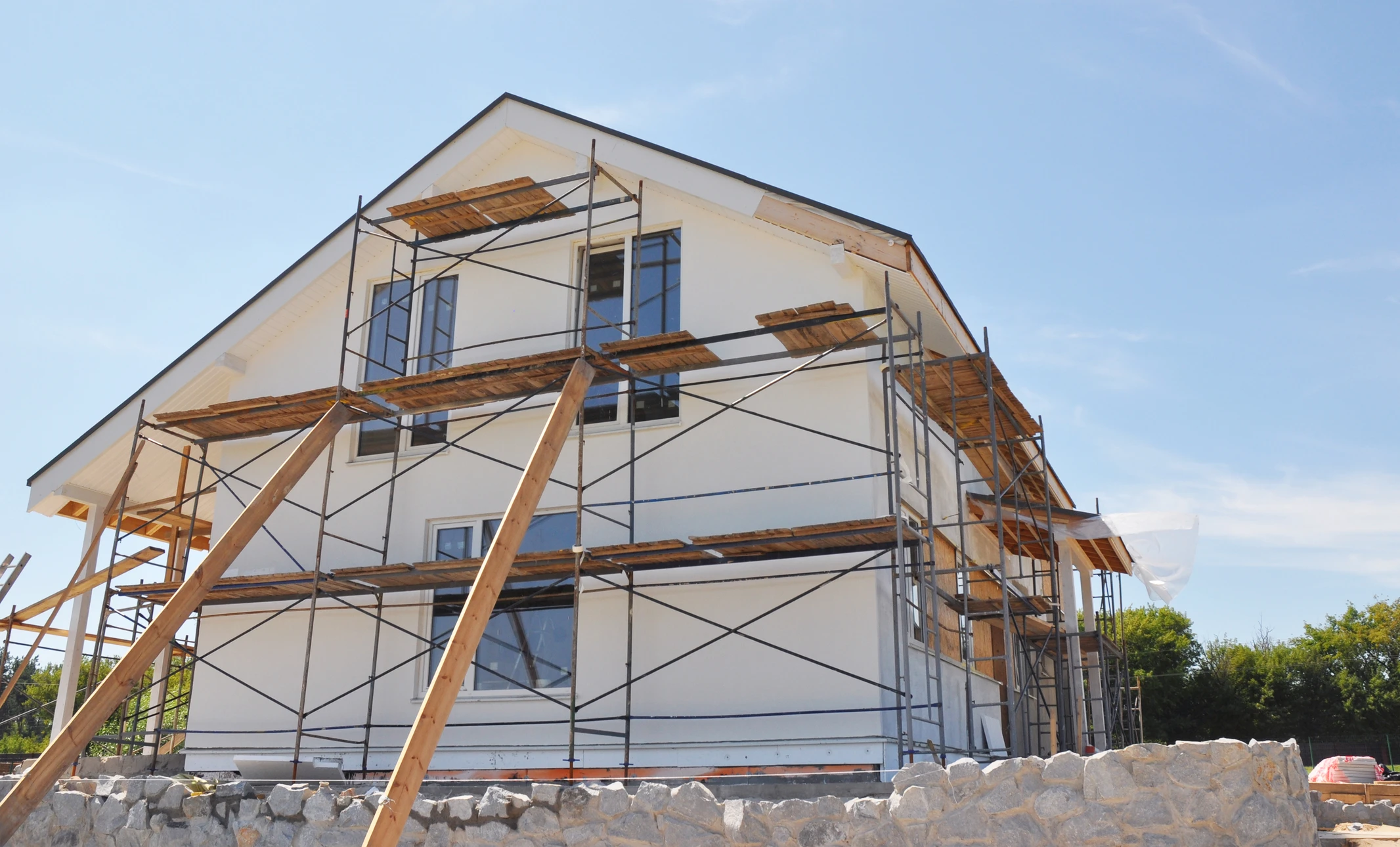 Photographier une maison en cours de ravalement de façade ou post-rénovation, montrant clairement les travaux d'enduit ou de peinture appliqués sur la façade, avec échafaudages visibles ou détails de finition récente. Alternativement, une maison rénoveée avec isolation thermique par l'extérieur visible, montrant une façade lisse et uniforme caractéristique des travaux ITE, avec des finitions de qualité professionnelle.
