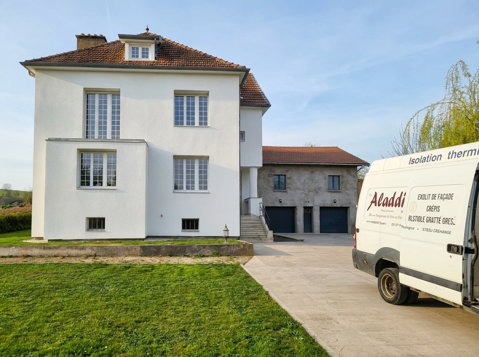 Ouvrier en bâtiment appliquant un enduit de façade extérieure depuis un échafaudage